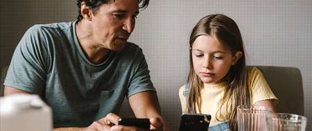 Father and daughter looking at their mobile phones