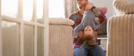 Man holding child upside down on his shoulder