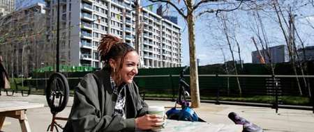 Woman sitting at picnic table drinking coffee laughing